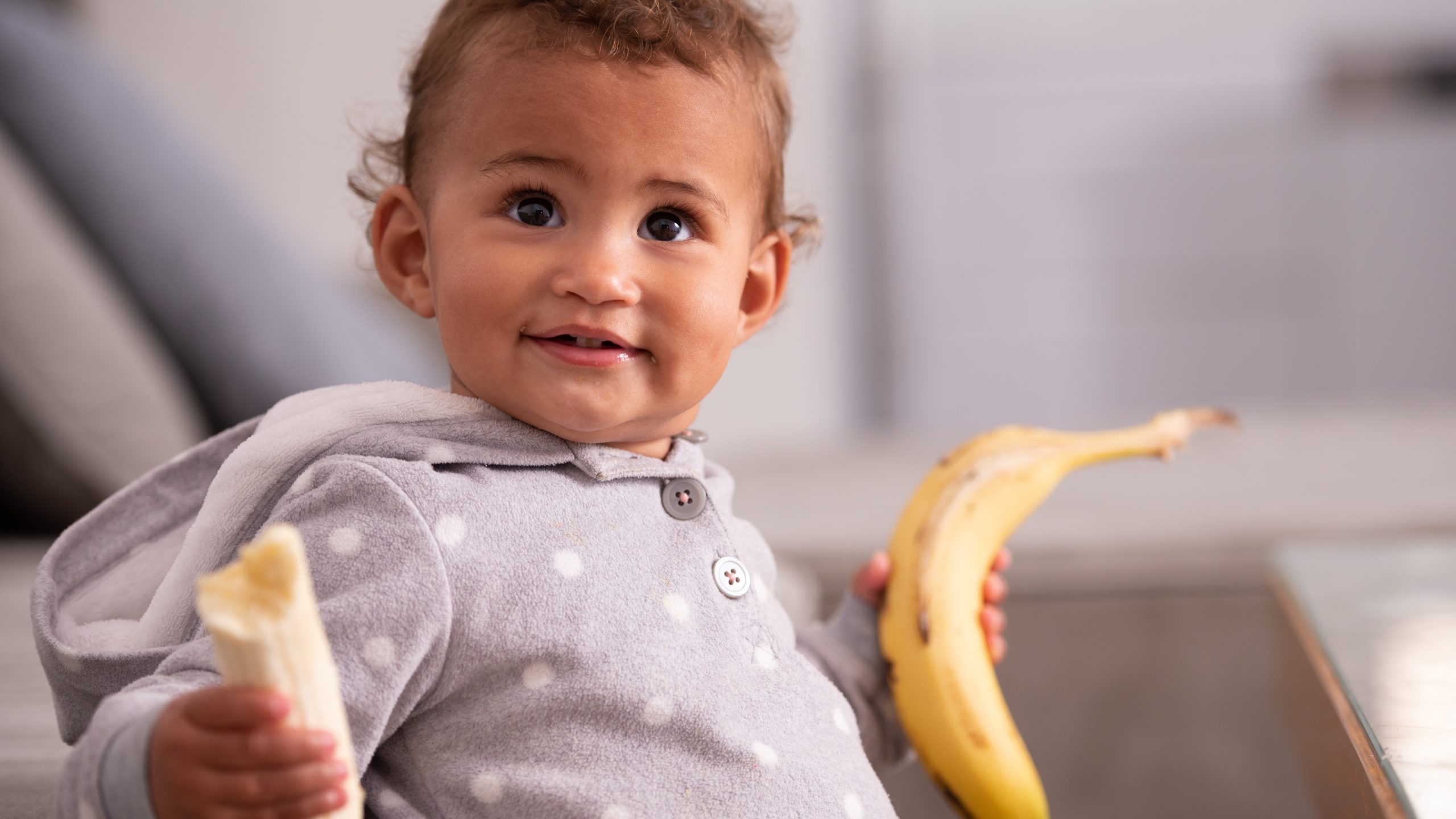 — title missing — Toddler eating a banana.
