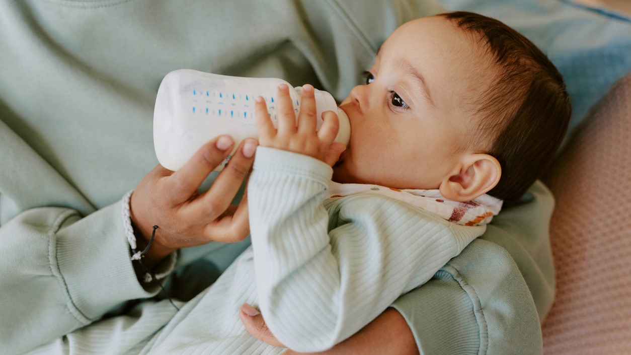 Baby drinking bottle Female caregiver holding baby and feeding a bottle.