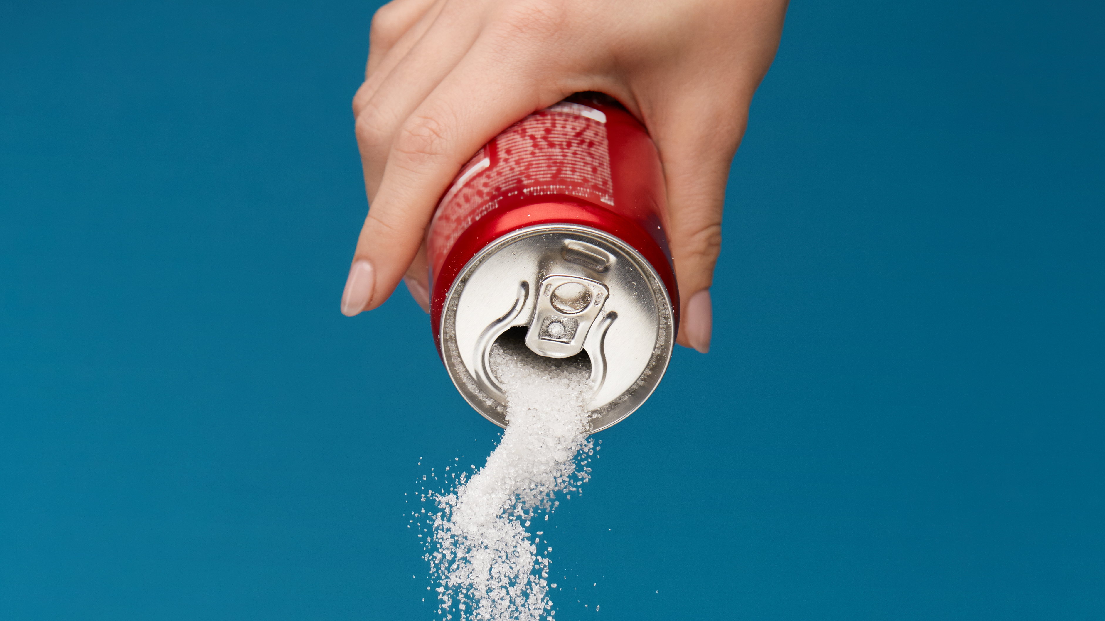 sugar-sweetened beverage Pouring out sugar from a sugar-sweetened beverage.