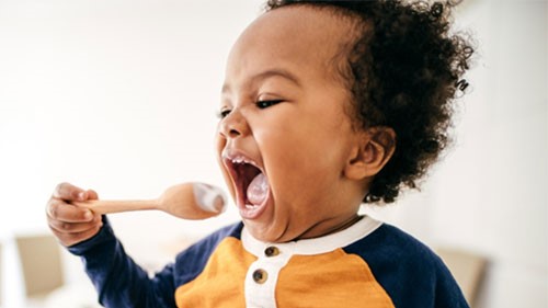 Zinc - yogurt A child eating yogurt from a spoon.