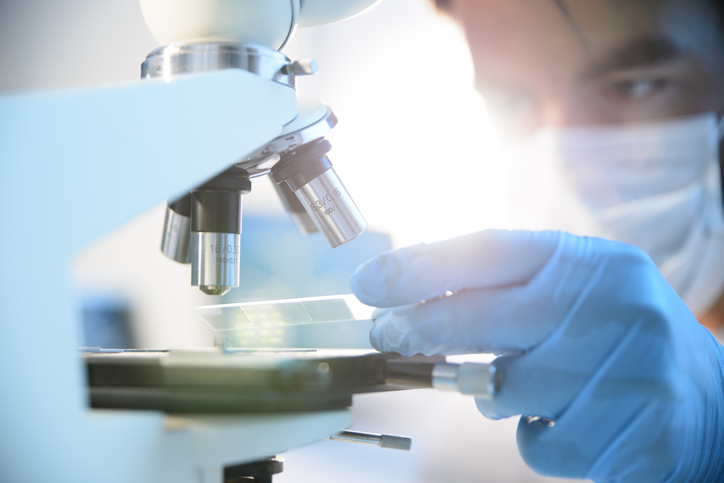 Person at microscope Person examining a specimen under a microscope