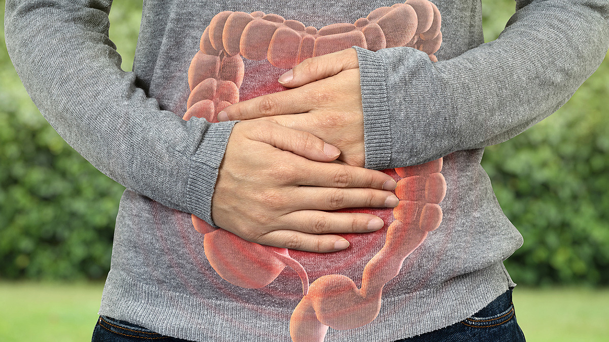 IBD Intestine Shirt Overlay A man outside holds hands on stomach with an illustration of bowels.