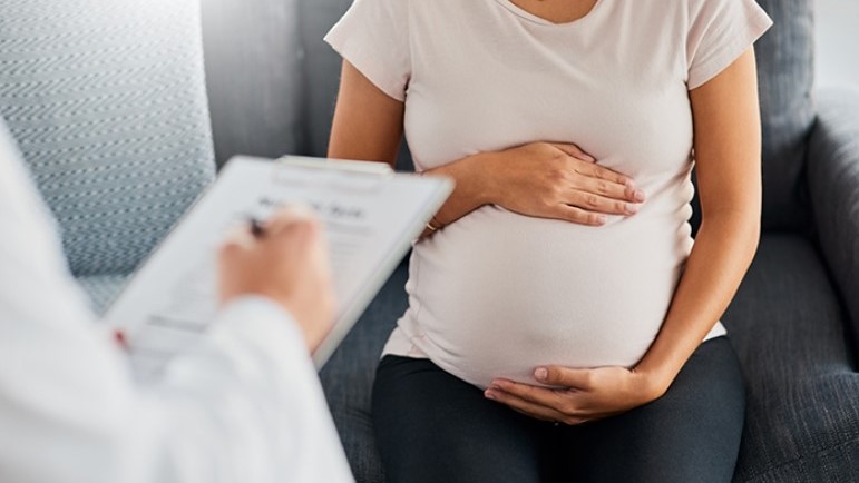 Pregnant woman in doctor's office holding her belly. Pregnant woman in doctor's office holding her belly.