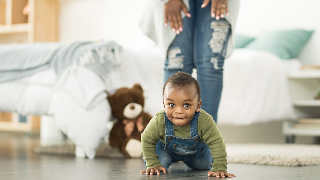 Toddler crawling on floor Small black male toddler crawling on floor towards the camera.