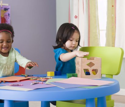 — title missing — Two children playing with toys while sitting at a table.