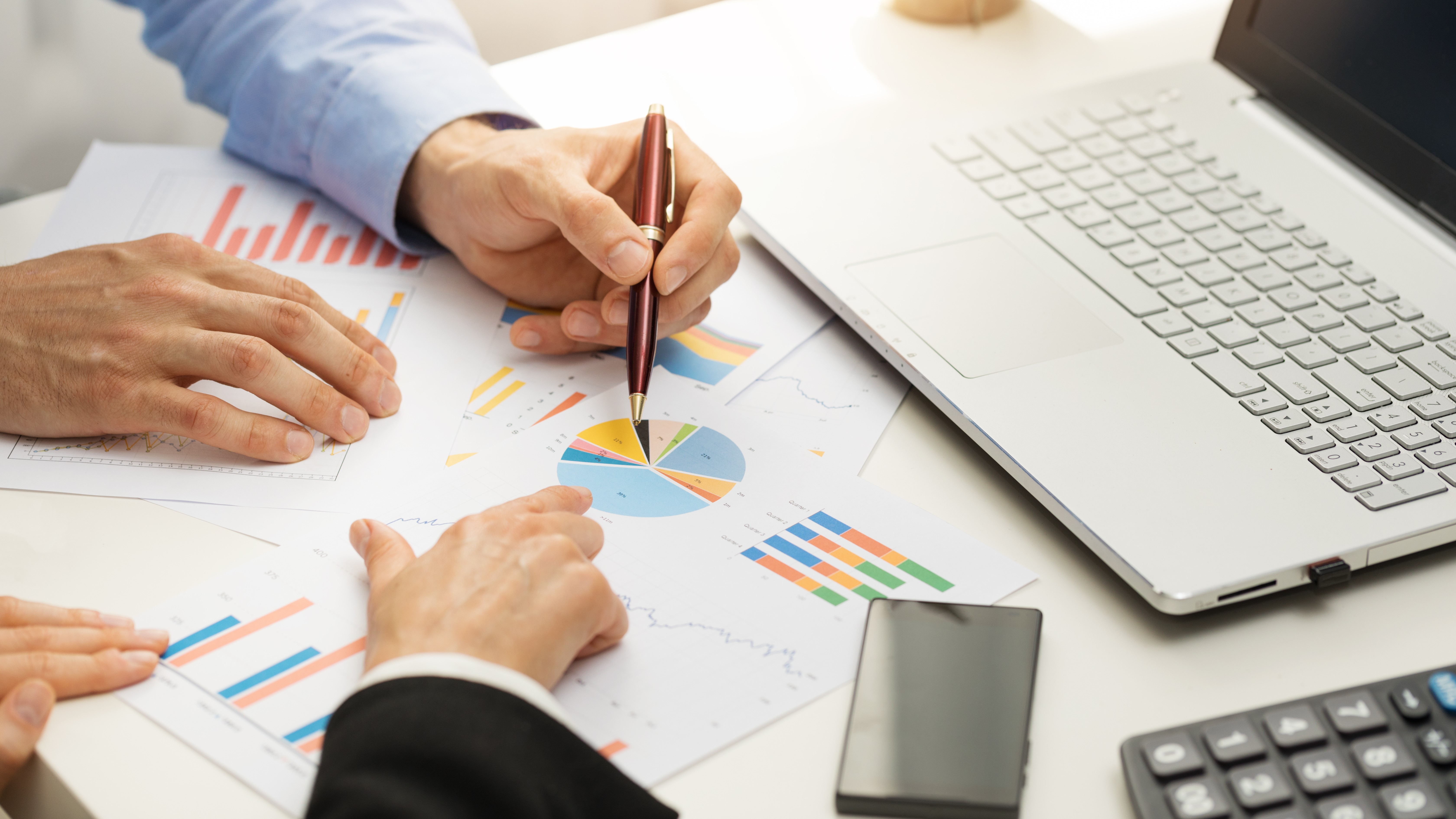 people at office analyzing business financial graph reports meeting table with people looking at graphs