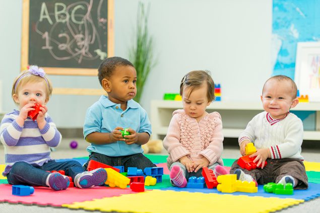 Babies playing Two toddler boys and two toddler girls play with toys in a preschool classroom.