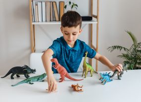 Boy playing with dinosaurs Young boy playing with toy dinosaurs on a table.