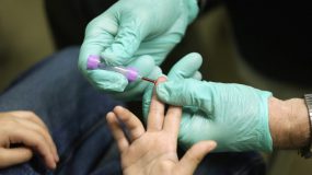 — title missing — A health care provider using a finger-prick to find the blood lead level of a patient.