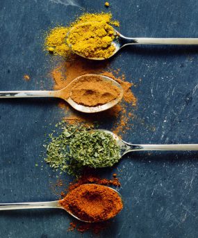 spicesinspoonssmall.jpg Powdered spices in spoons sitting on a table.