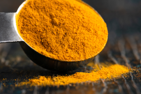 Spoonful of spice A spoonful of orange spice with some spilling onto a table.