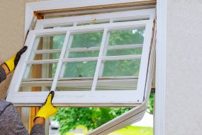 Window replacement A person wearing gloves holding a new window.