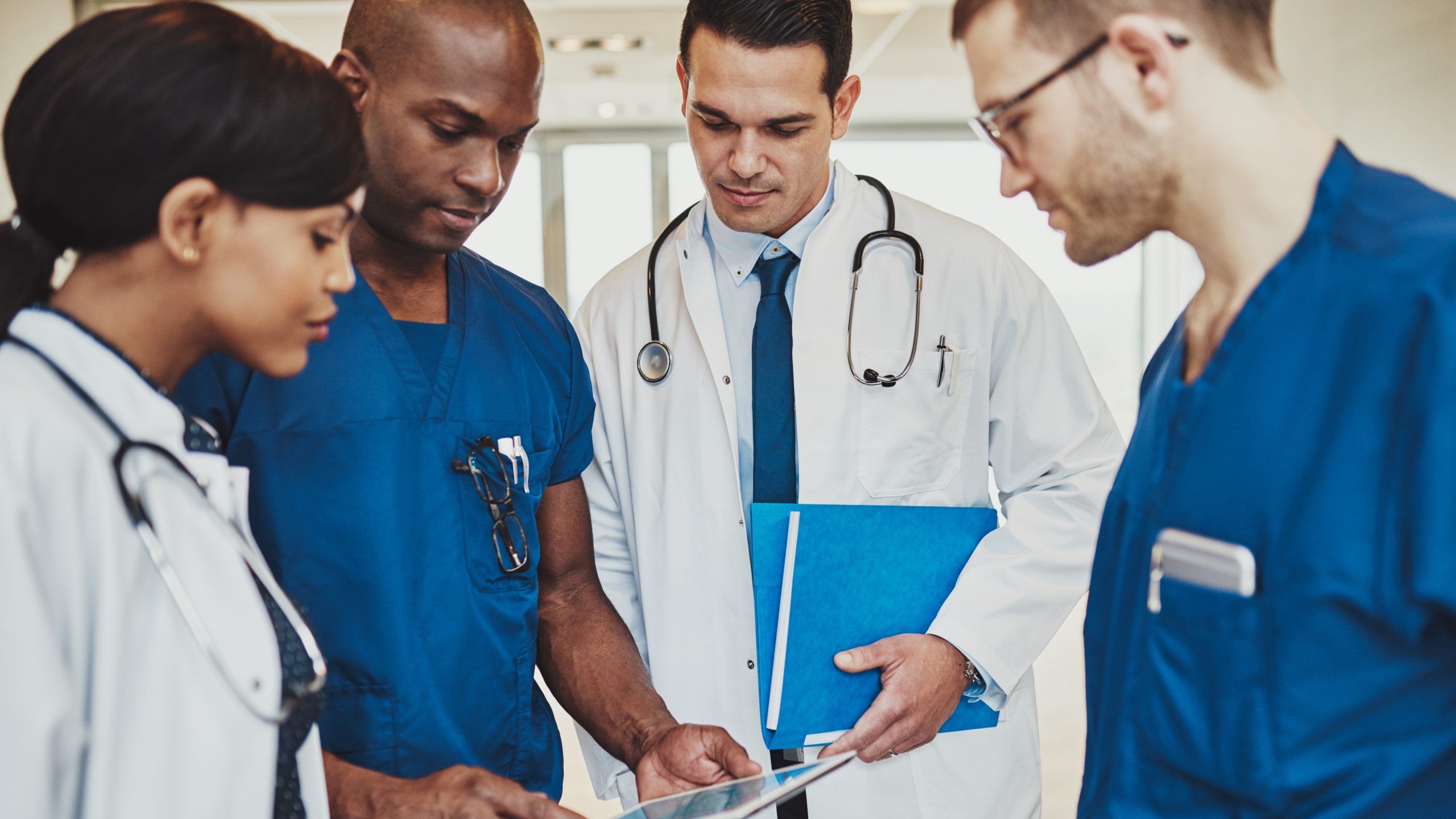 HCPs huddle around tablet Healthcare providers huddle together and look down at a tablet
