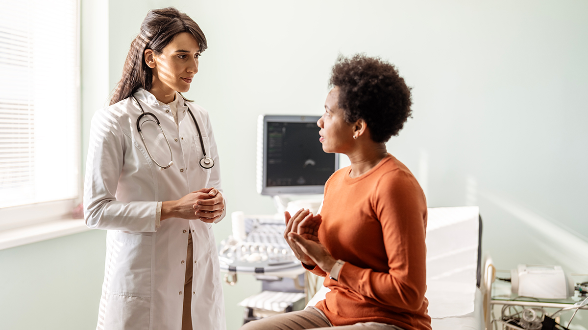 Strategies to Prevent Worsening of Symptoms A female doctor talks with her patient in front of her as they talk about her concerns. - stock photo