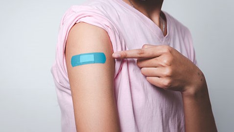 girl vaccinated blue bandage Young person pointing to an adhesive bandage on her arm after injection of vaccine.