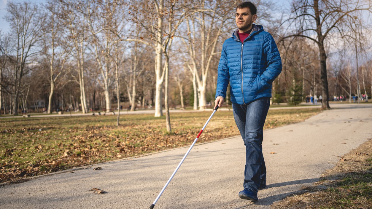 man with disability walking using a cane Man walks using a walking cane.
