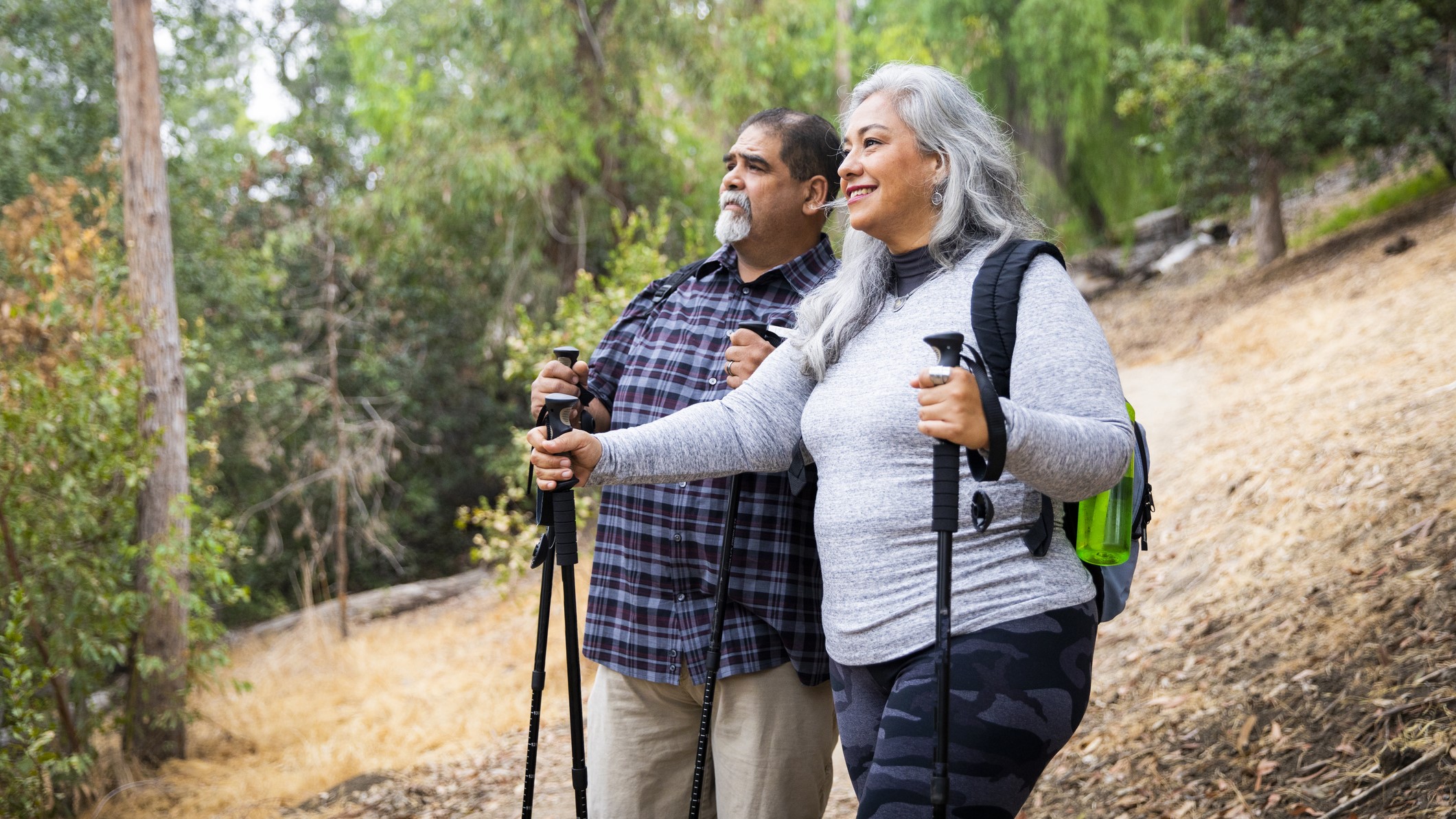 Older Couple Hiking _16-9_1 Older couple with backpacks and walking sticks going on a hike.