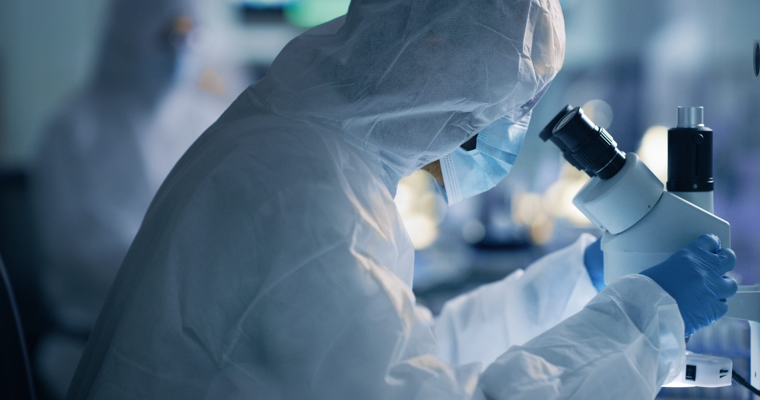 Laboratory staff in PPE A laboratorian works at a microscope in full PPE
