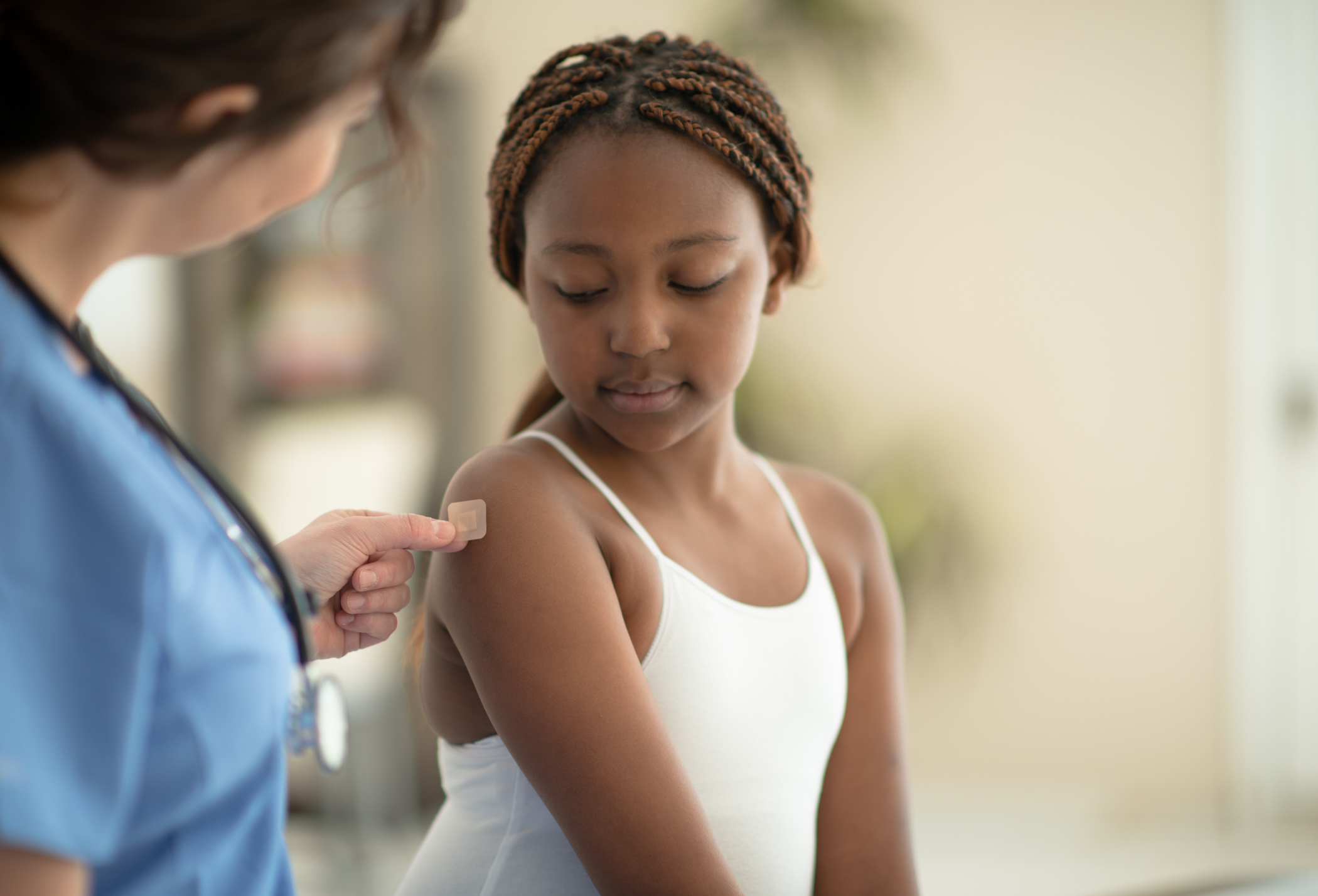 Getting vaccinated Young girl gets a band-aid over her injection site at the doctor’s office.