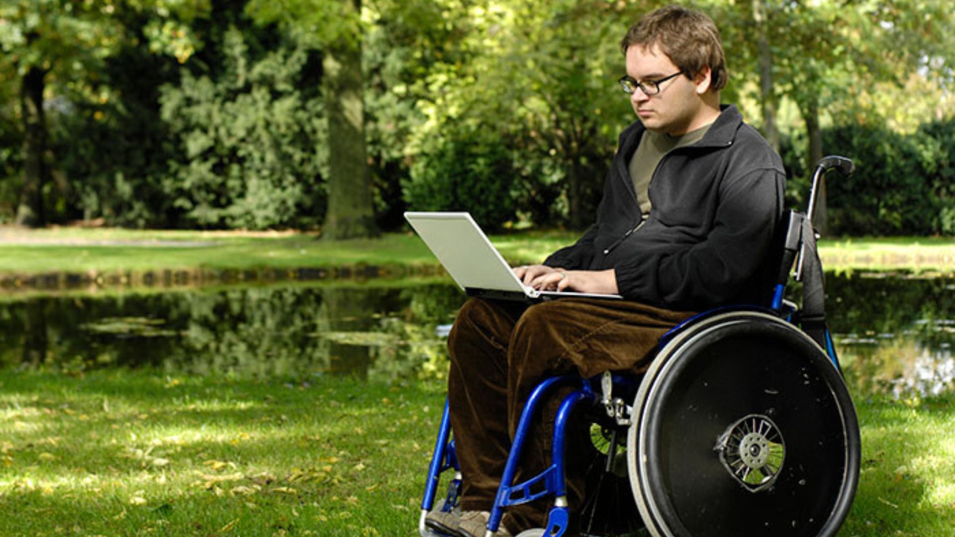 Teen in wheelchair Niño adolescente en silla de ruedas mirando una computadora portátil.