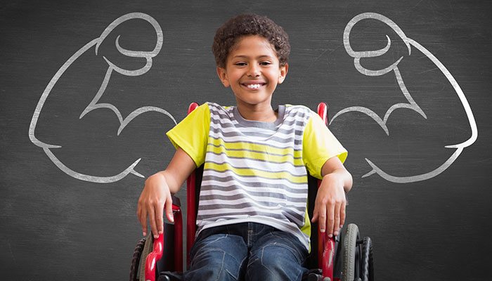 strongboyinwheelchair700px.jpg Smiling young boy in wheelchair with muscular arms drawn in chalk on blackboard behind him