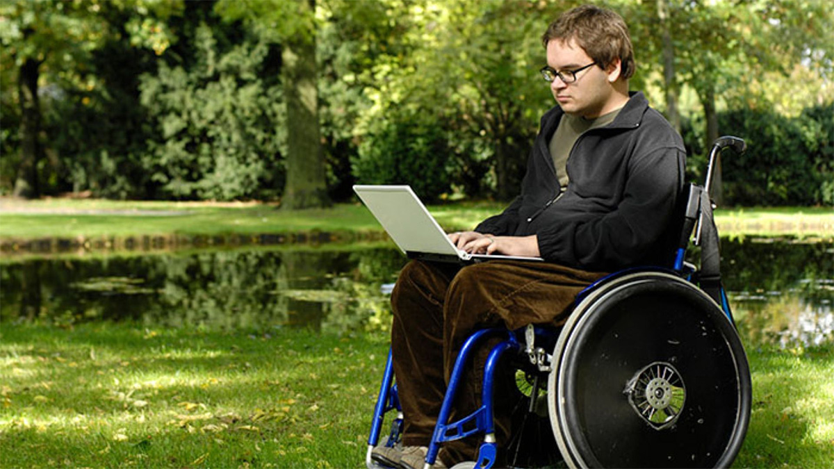 Teen in wheelchair Teen boy in wheelchair looking at laptop