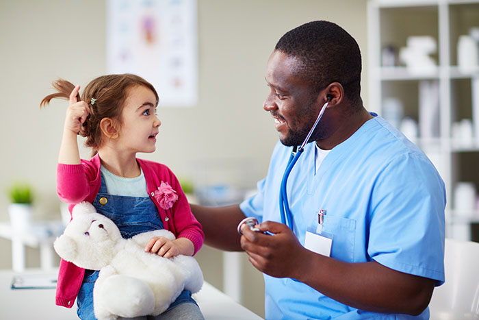 Little girl holding a teddy bear, talking to a doctor Little girl holding a teddy bear, talking to a doctor