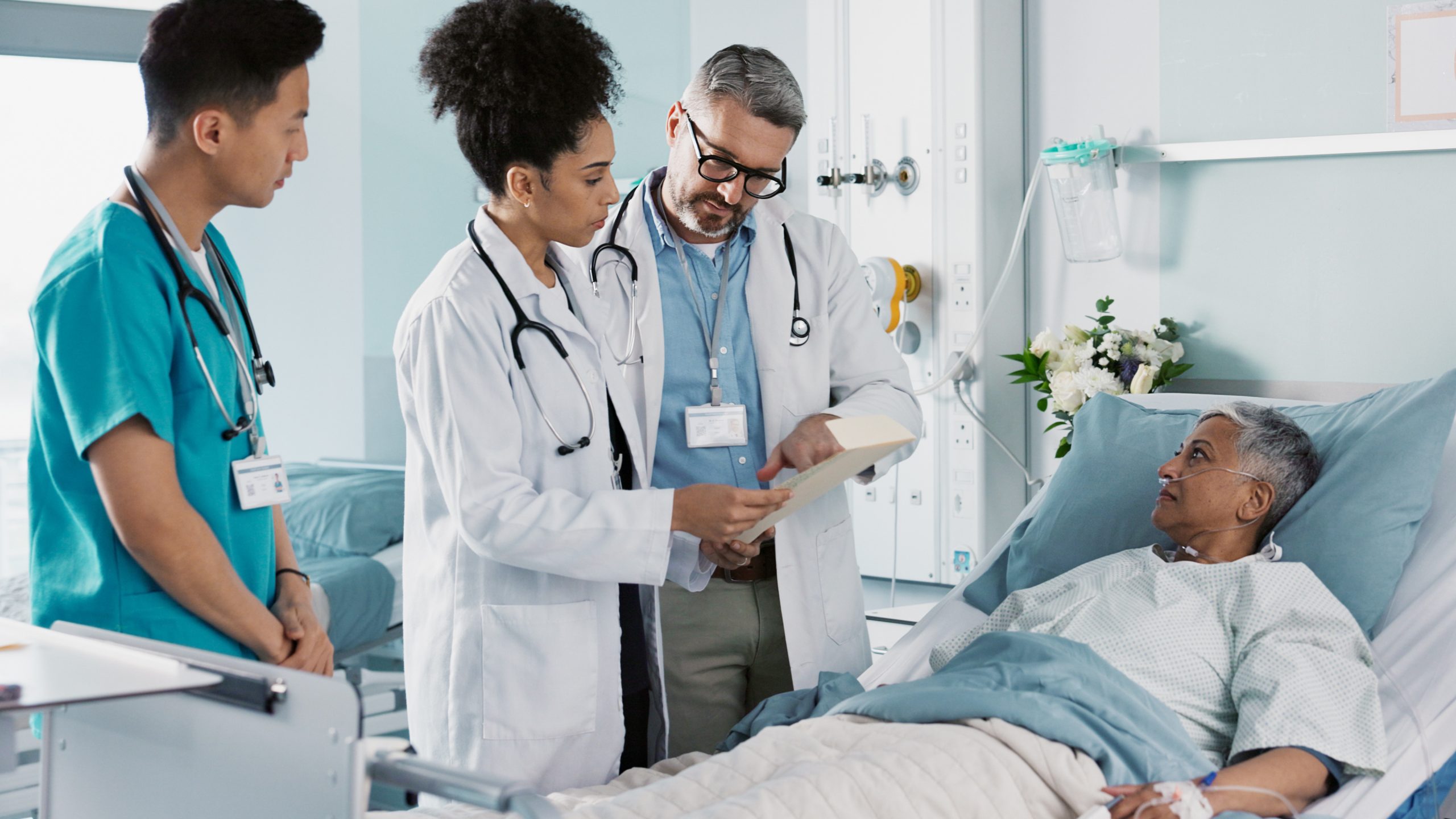 Doctors and Patient Two male doctors and a female doctor next to a patient's bed in a hospital