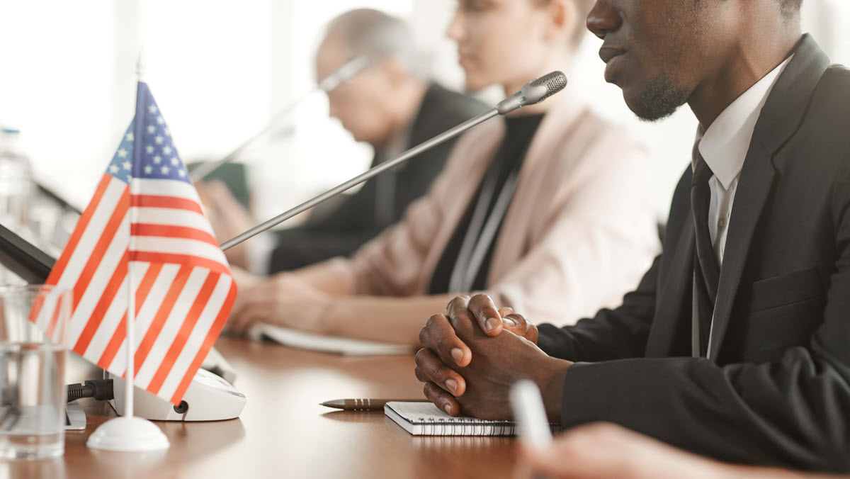 Advisory_board_1200x675 A man speaks into a microphone at a meeting.