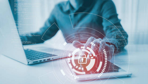 gettyimages-1267995157-522x293 Person uses a laptop and a tablet. A red circle of data with a lock hovers over the laptop.