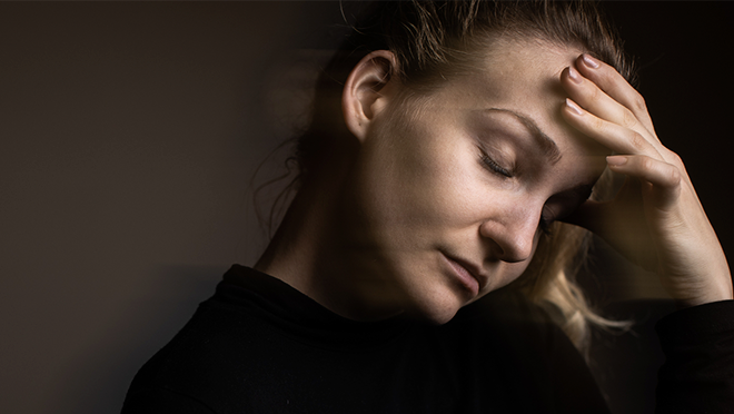 Lady holding her forehead with eyes closed.