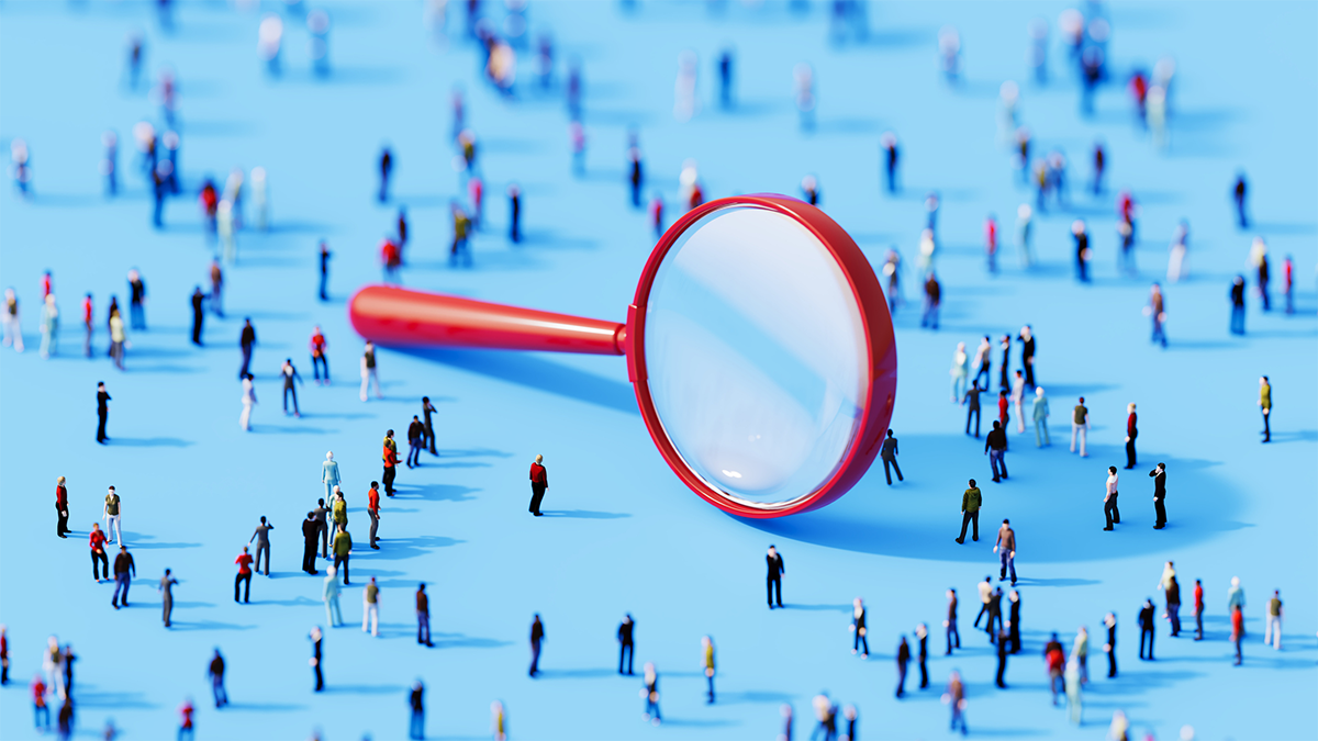 A large magnifying glass focusing on a crowd of miniature people on a blue background, symbolizing search or analysis.