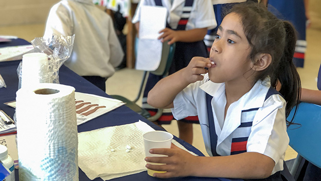 Child receiving medication as part of MDA campaign Girl in school uniform taking mediation