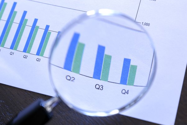 Image shows a magnifying glass held over a bar graph. Bar graph axes and labels are not visible.