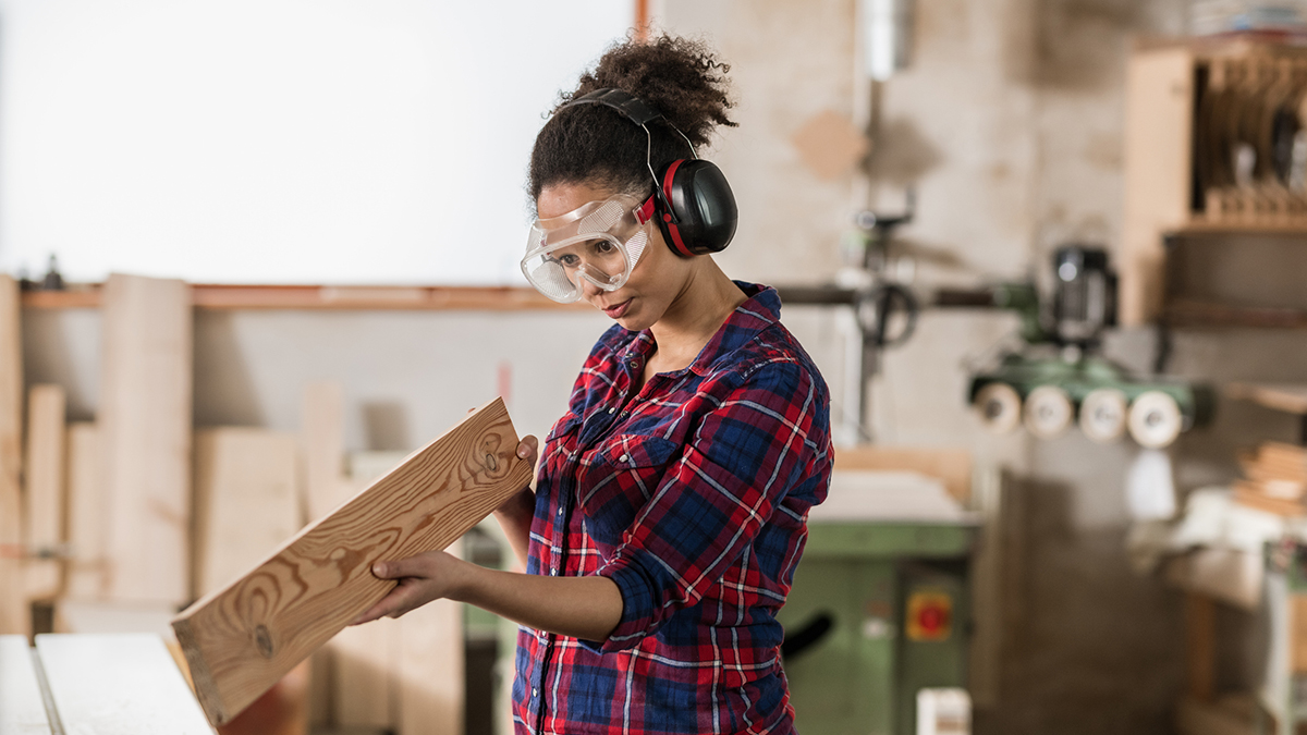 1142638113 Pregnant woodworker wearing eye and hearing protection.