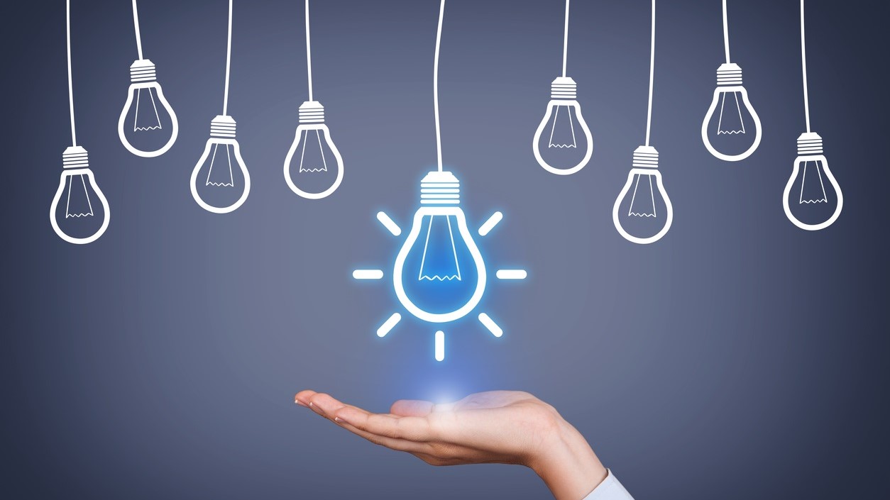 Idea lightbulb Illustration of hanging lightbulbs. The center one lit with a gesturing hand underneath it.