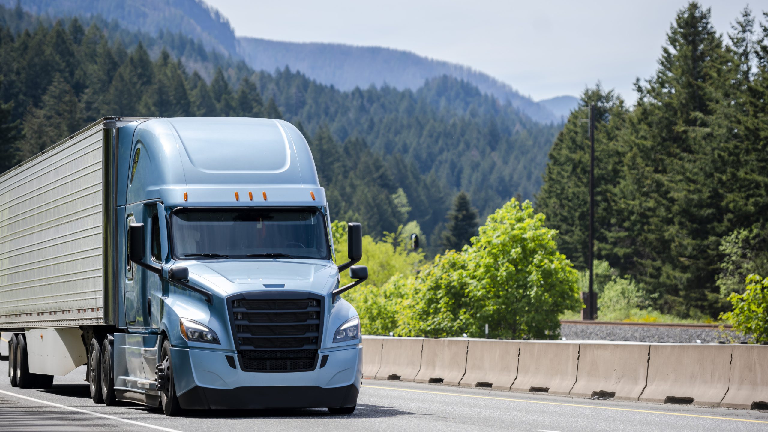 long-haul truck driver A blue semi-tractor trailer driving through the mountains.