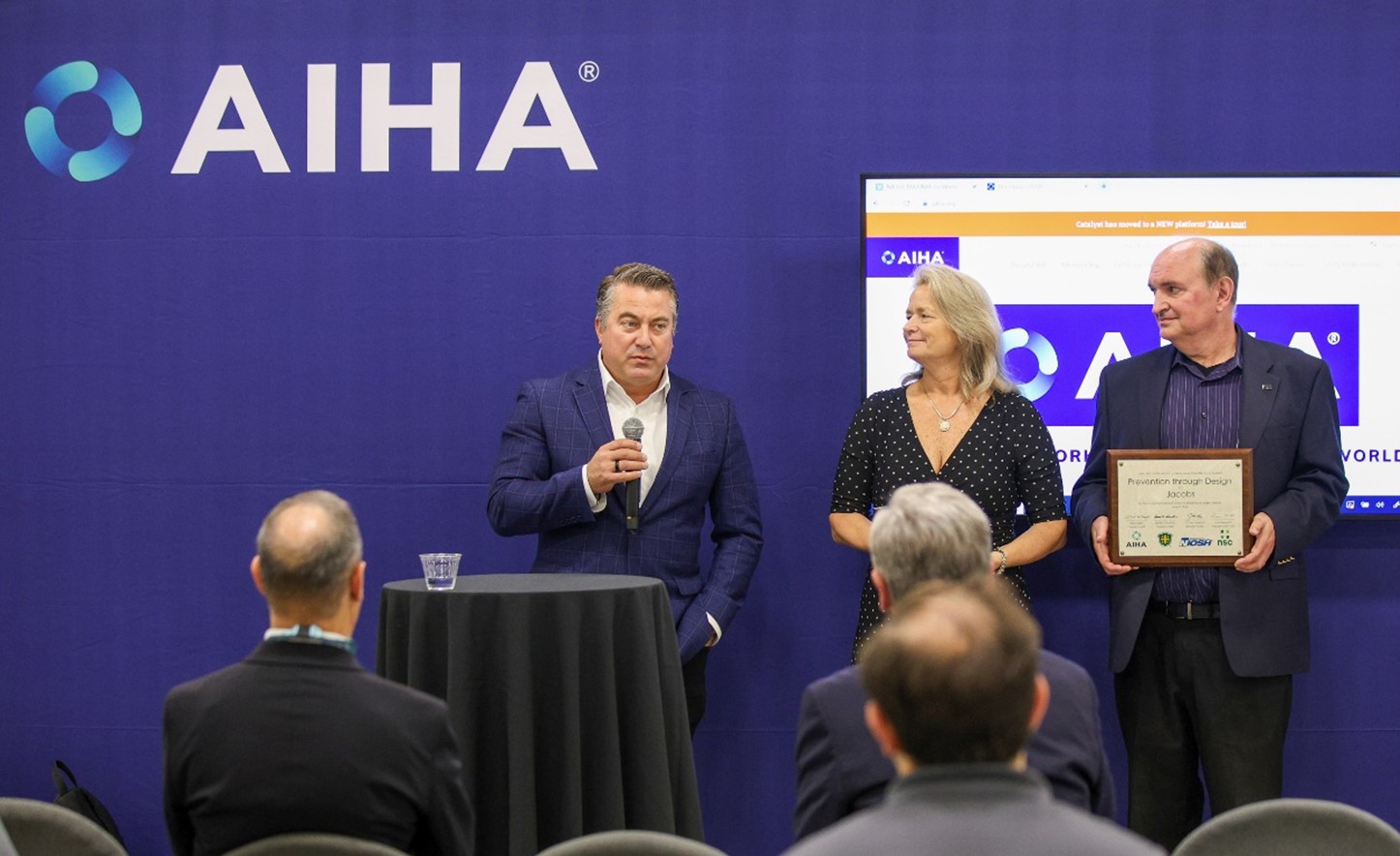 2024 PtD Awardee: Jacobs Solutions, Inc 2 men wearing suits and a women in a dress accepting the 2024 PtD award