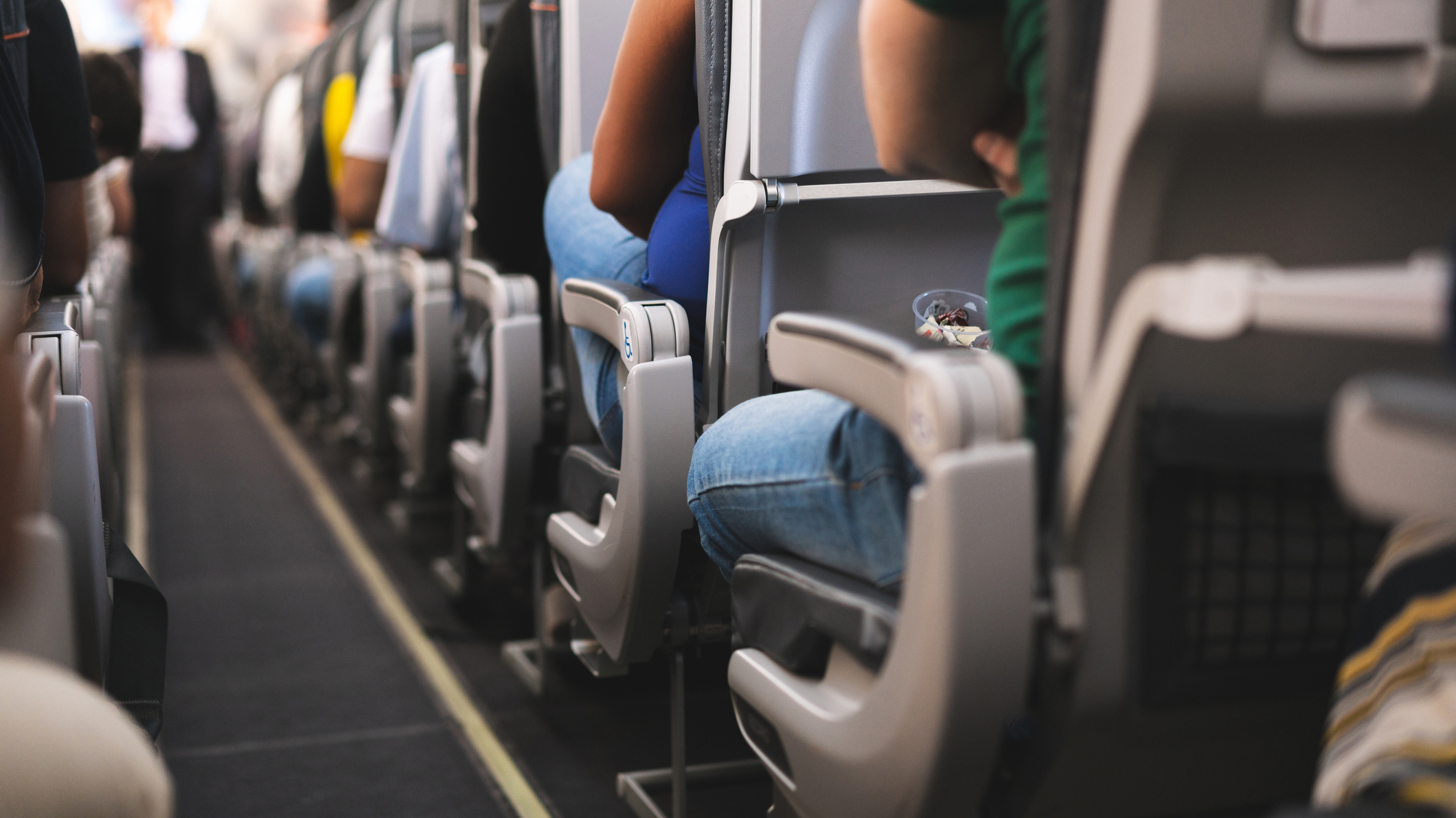 1140467574 Inside of a commercial aircraft and passengers shown from the rear of the cabin.