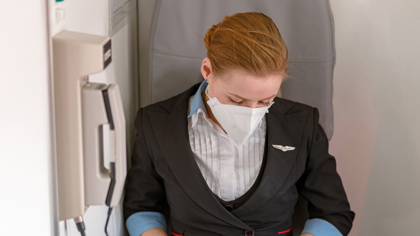 1364780446 Female aircrew member seated aboard a commercial aircraft.