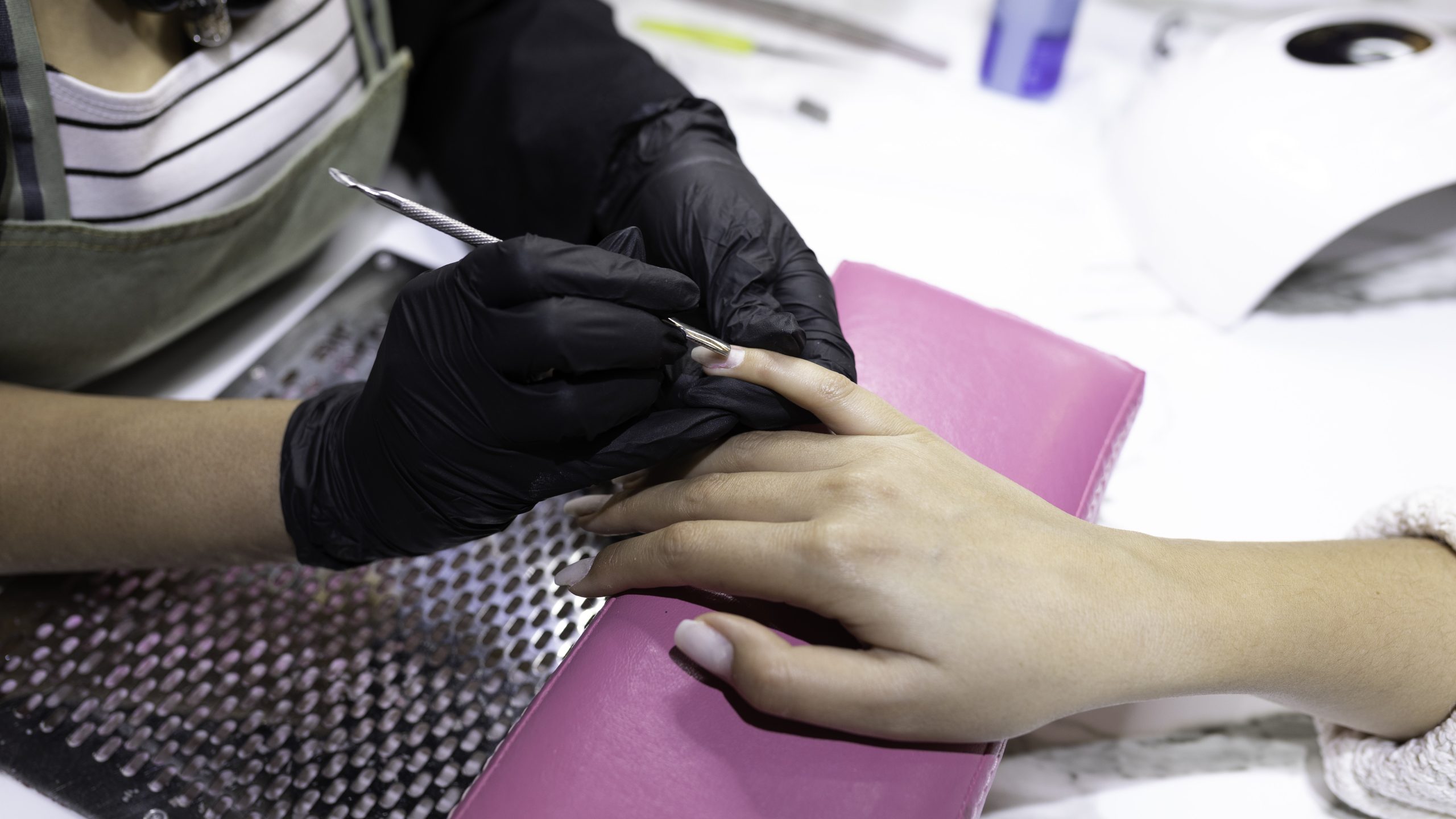 Nail Technician Manicure Nail technician wearing gloves and performing manicure over ventilated table
