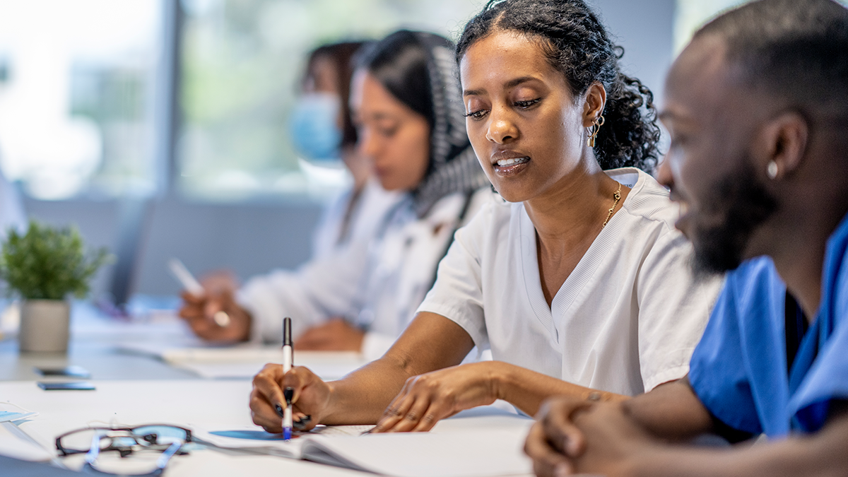 Tips for Communicating Effectively 1 Row of adult students in scrubs sitting along one side of a table.
