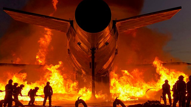 Seattle fire dept. copy Firefighters fighting a fire near a burning airplane.