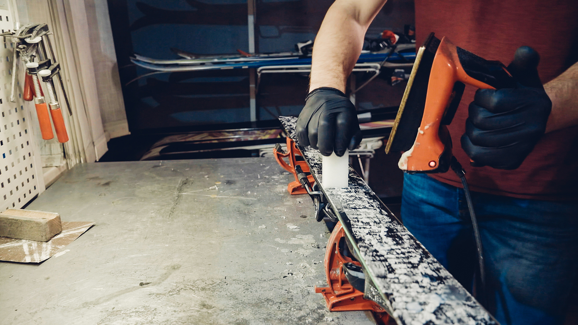 1196415915 A worker waxing a ski on a bench.