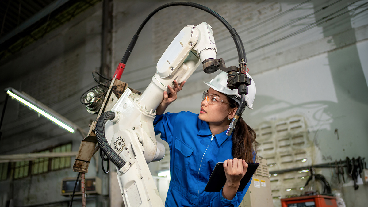 DSR Image Photo of a young black woman with a hard hat working near a robot.