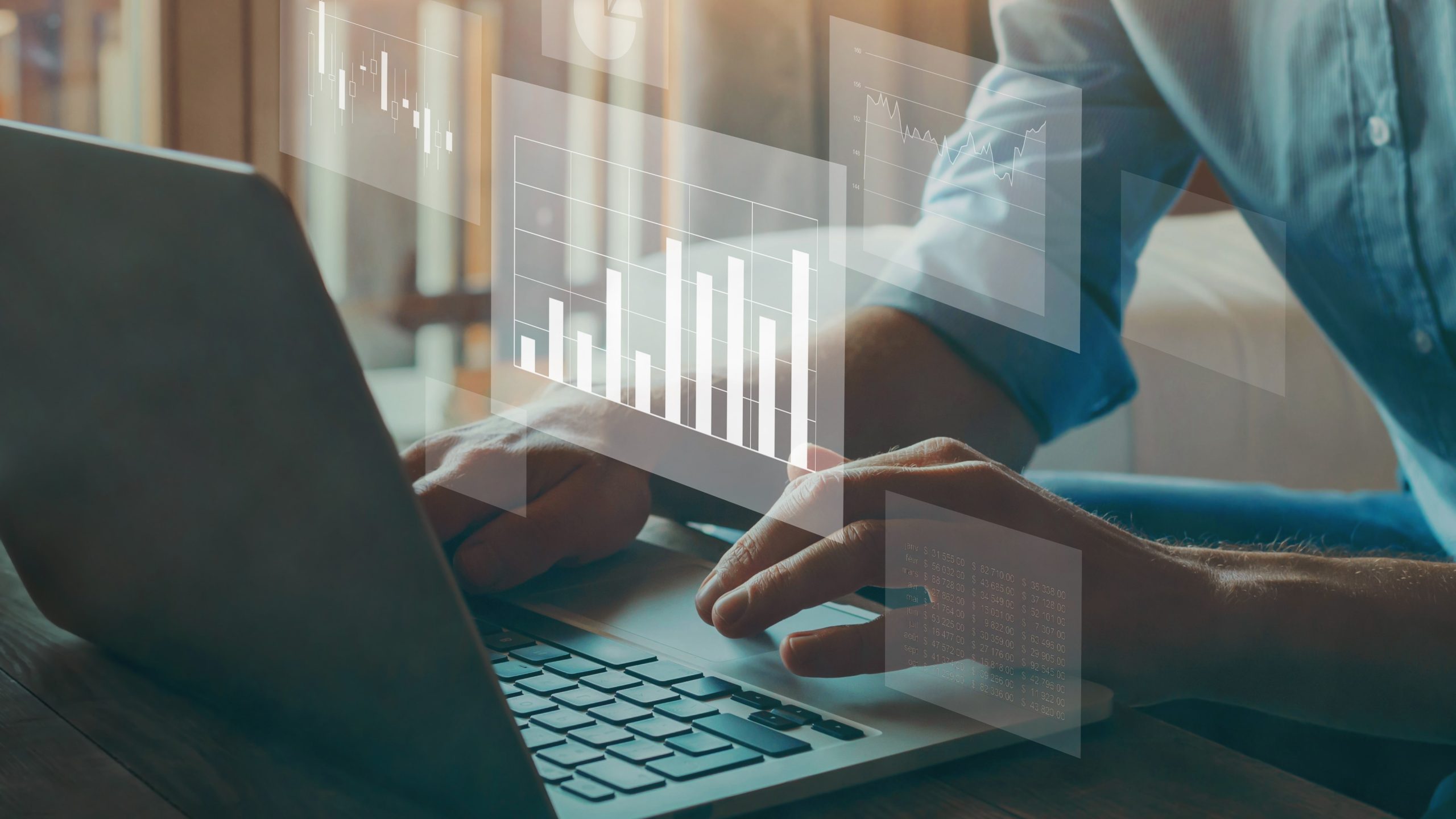 Data analytics Hands typing on a laptop with small, transparent charts and graphs.