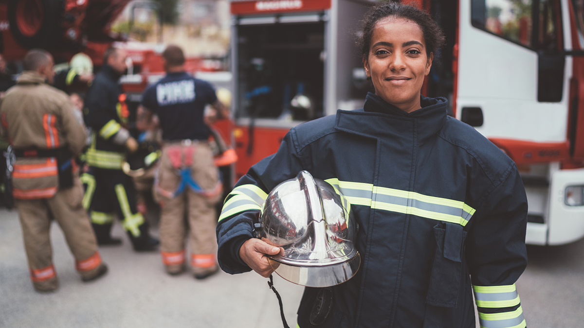 1048690130 Pregnant firefighter in foreground, with other firefighters in the background.
