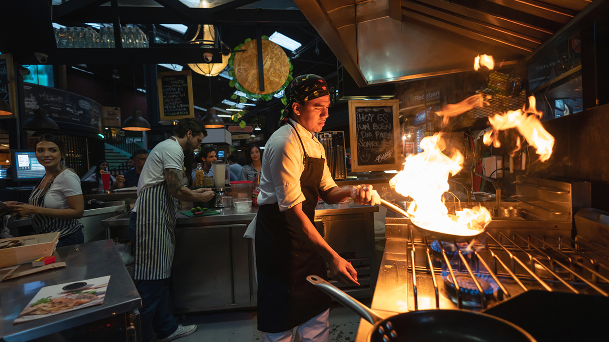 1160815693 Chef cooking at a restaurant flaming the food - small business concept