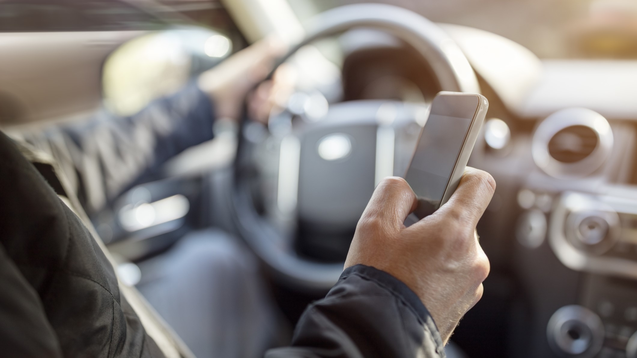 Distracted_Driving Driver with one hand on wheel and the other hand using a cell phone