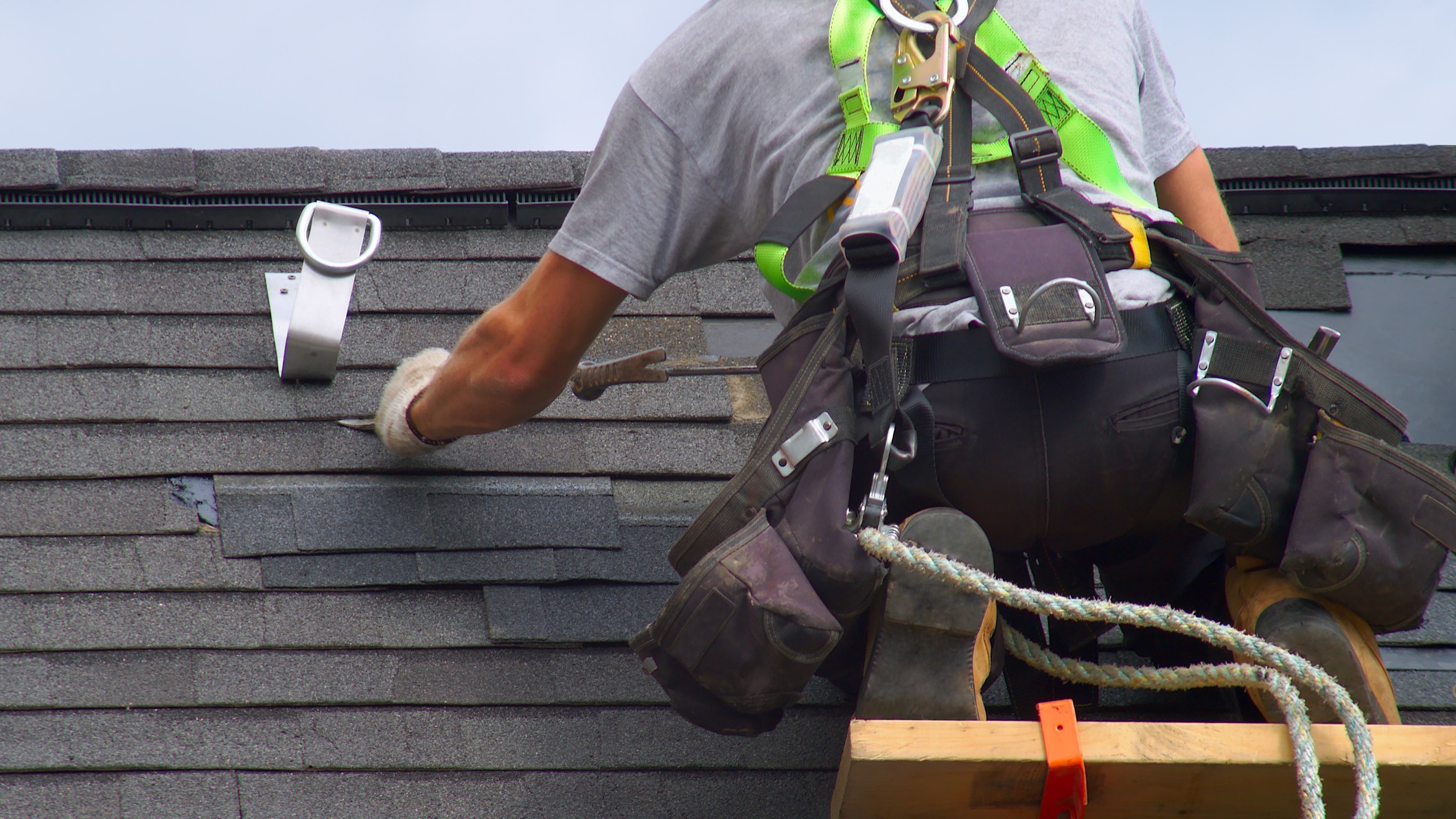 — title missing — A man is on a roof working on shingles. Photo credit Getty images/jacquesdurocher.